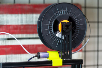 A photo showing a horizontal mounting position under the filament spool using the cross piece of the gantry on a bed-slinger style printer.