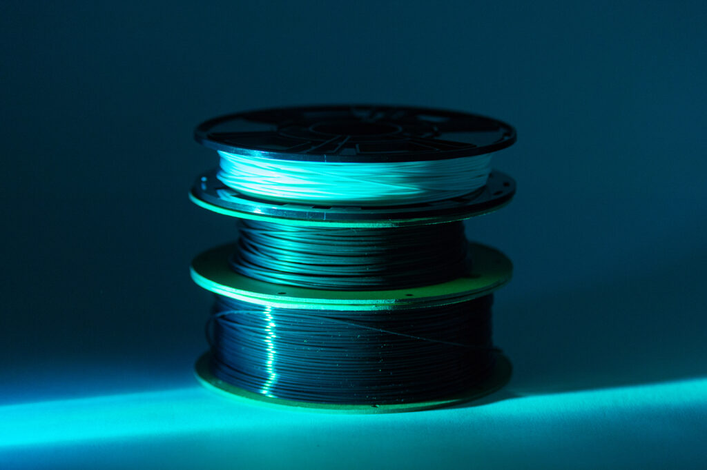 Here is a photo of 3 spools of filament stacked with a blue beam of light hitting them.